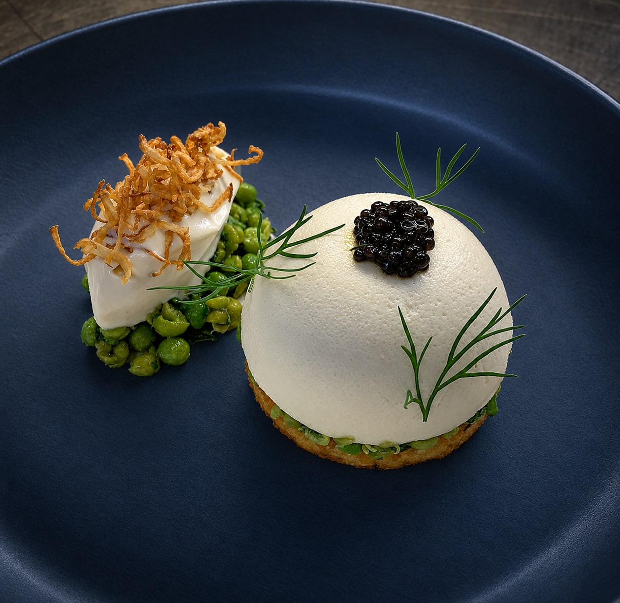 A caviar-topped course with peas and delicate herbs on a slate-blue plate