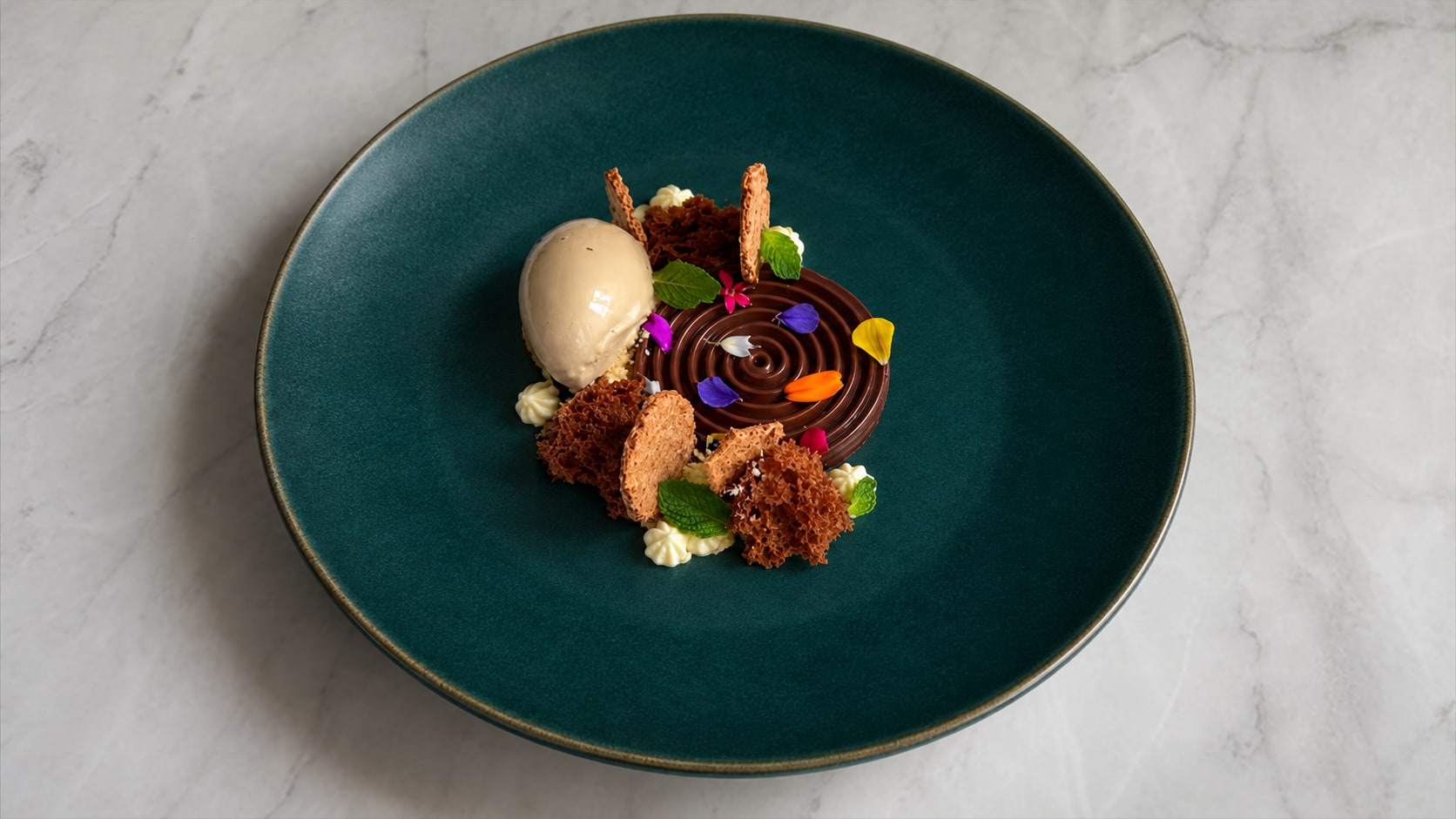A composed chocolate dessert on a teal plate